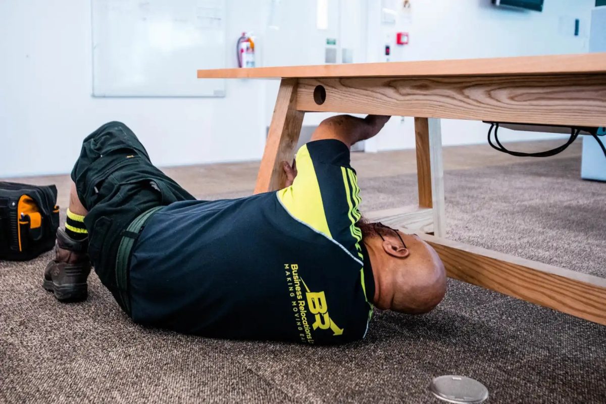 Minimising business downtime – Business Relocations employee adjusting a table for an office move